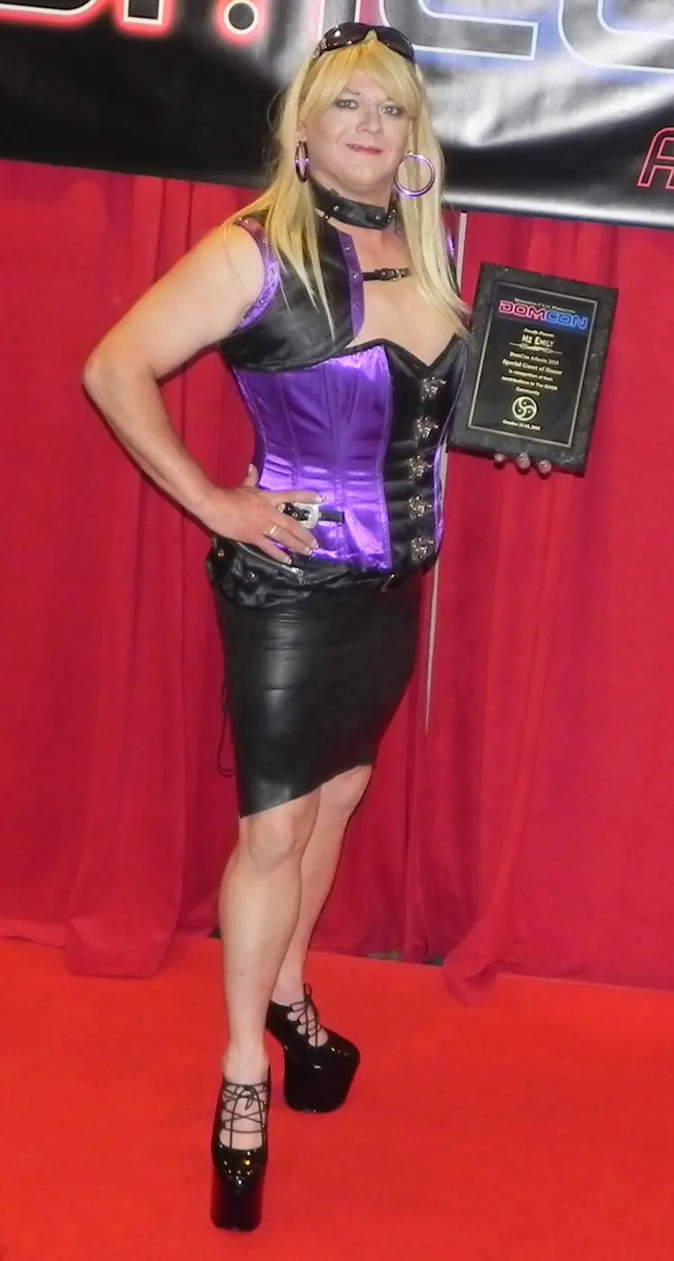 Mz Emily holding an award plaque at a DomCon event